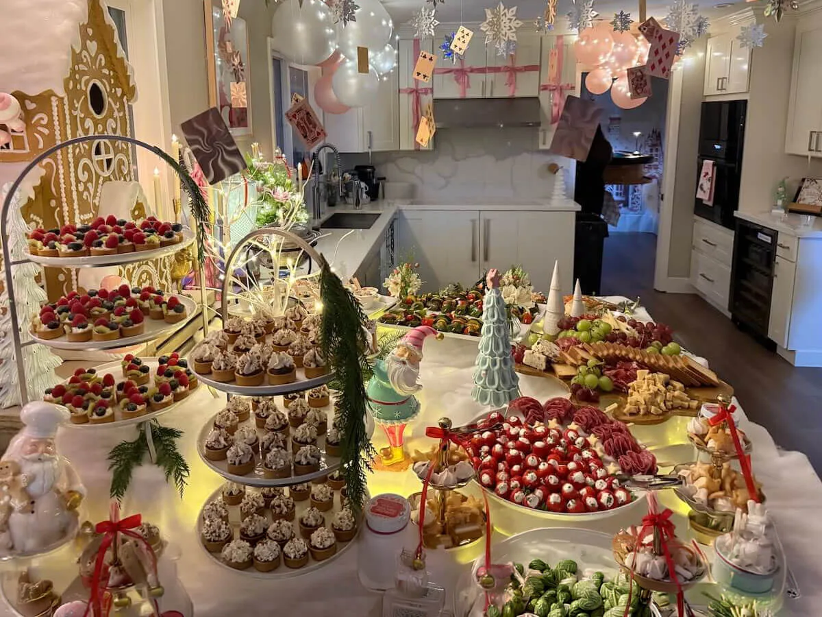 Styled tablescape of tiered tarts, frosted cupcakes and cured meats with pastel balloons floating above