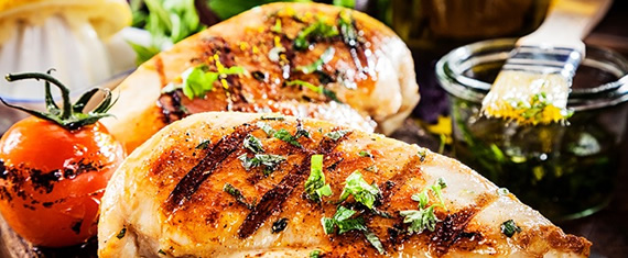 Grilled chicken breasts with green toppings and tomato