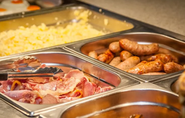 Breakfast catering buffet for a company consisting of sausage, eggs, and ham.