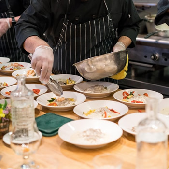 A chef is putting vegetable dish in plates for catering in SF