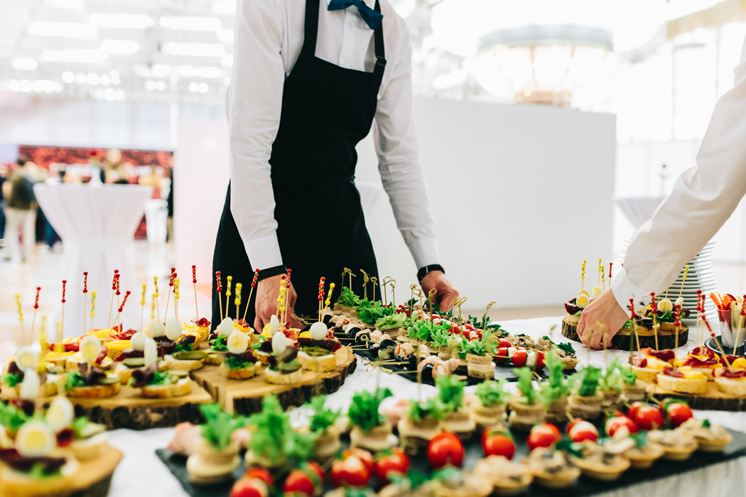 Waiters serving appetizers on the white table for wedding catering